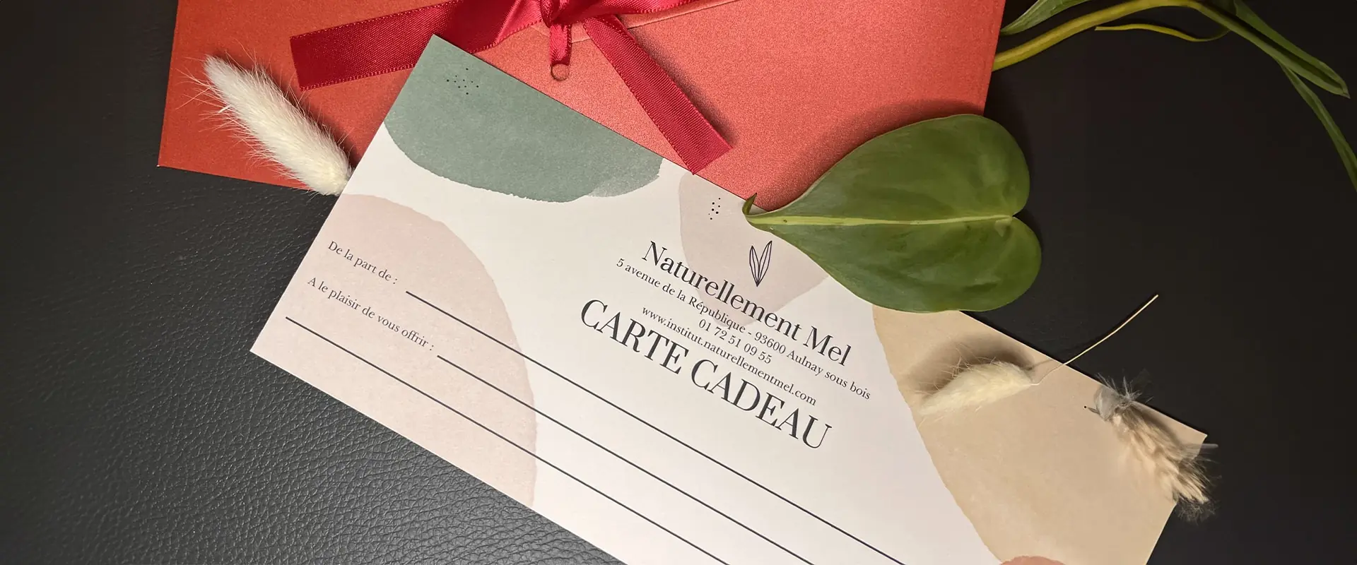 Carte cadeau Naturellement Mel présentée avec son enveloppe et une décoration végétale